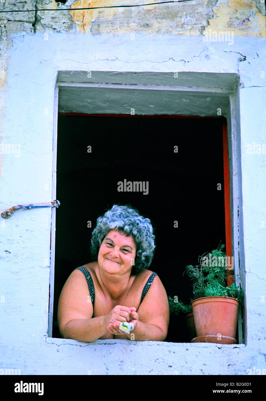 large woman smiles from a villa window in malta Stock Photo