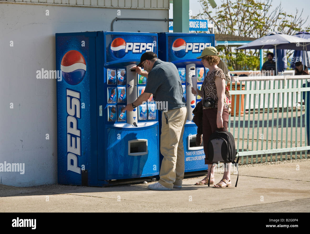 Adult man and woman buying Pepsi from a vending machine on a hot sunny day Stock Photo