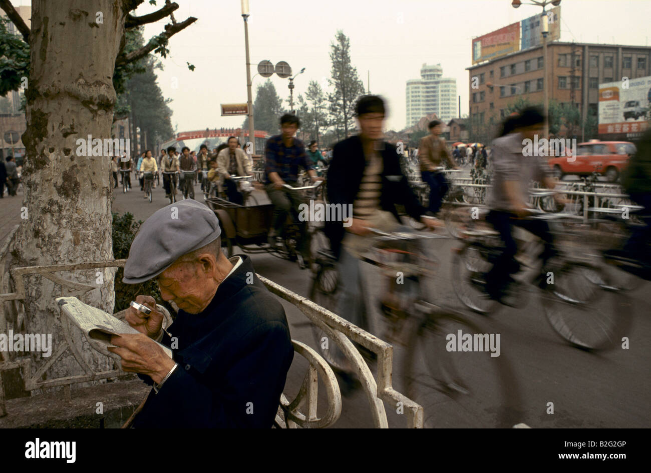 man reading newspaper on busy chinese street Stock Photo