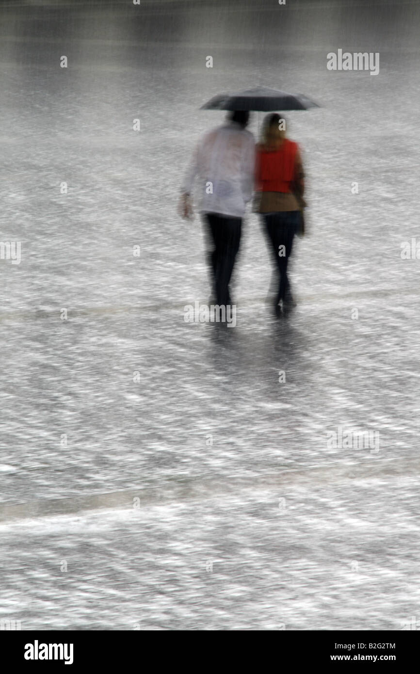 young couple sharing an umbrella in heavy rain Stock Photo - Alamy