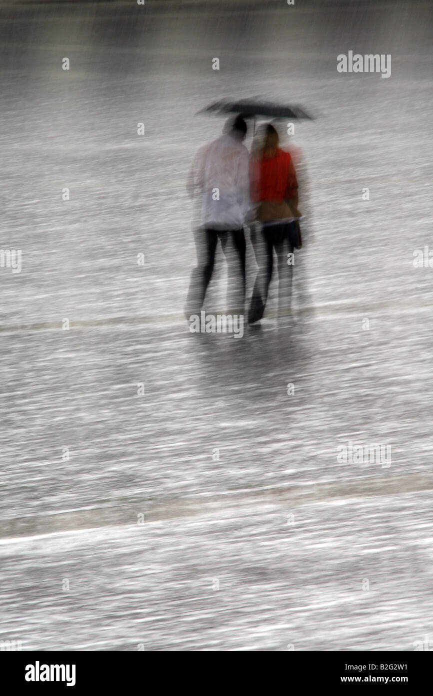 young couple sharing an umbrella in heavy rain Stock Photo - Alamy