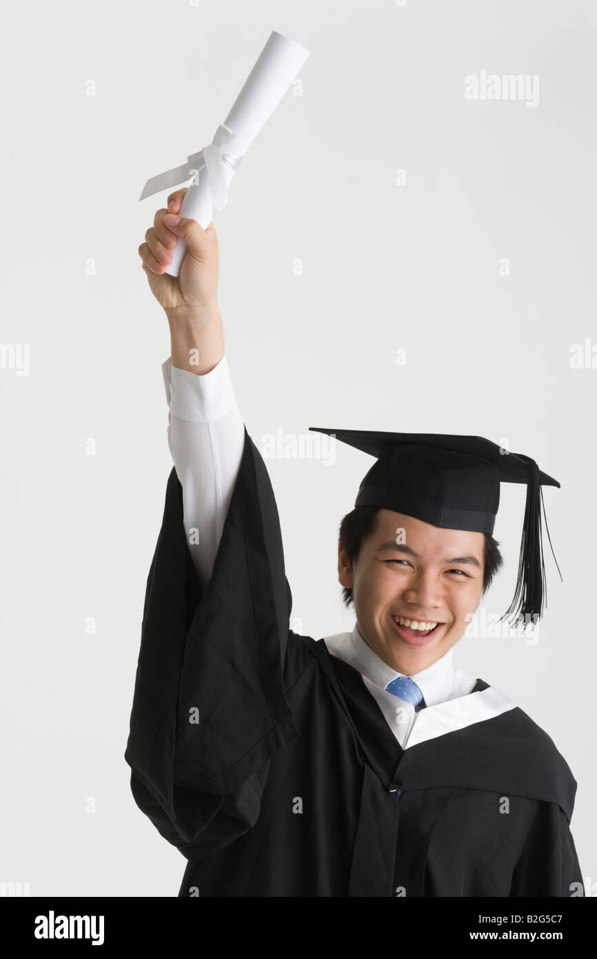 Portrait of a young male graduate holding a diploma with his hand ...
