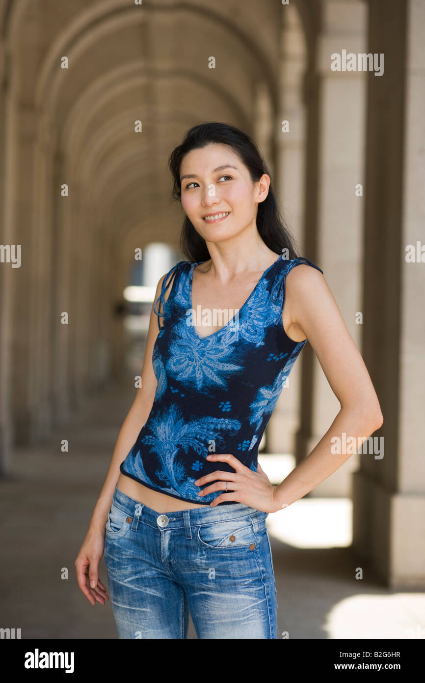 Young woman standing with her hand on her hip and smiling Stock Photo ...