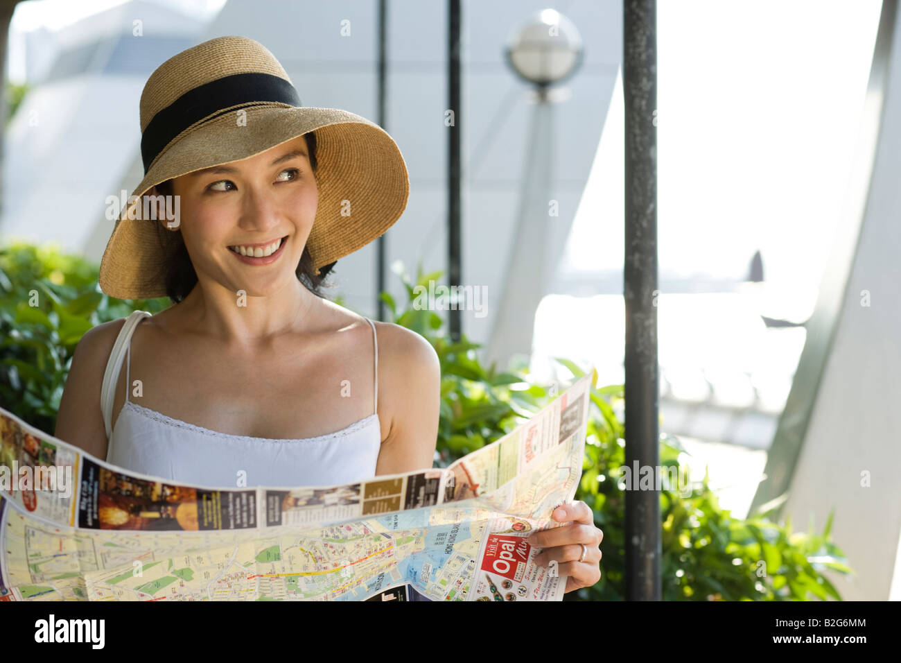 Young woman wearing a sun hat and holding a map Stock Photo - Alamy