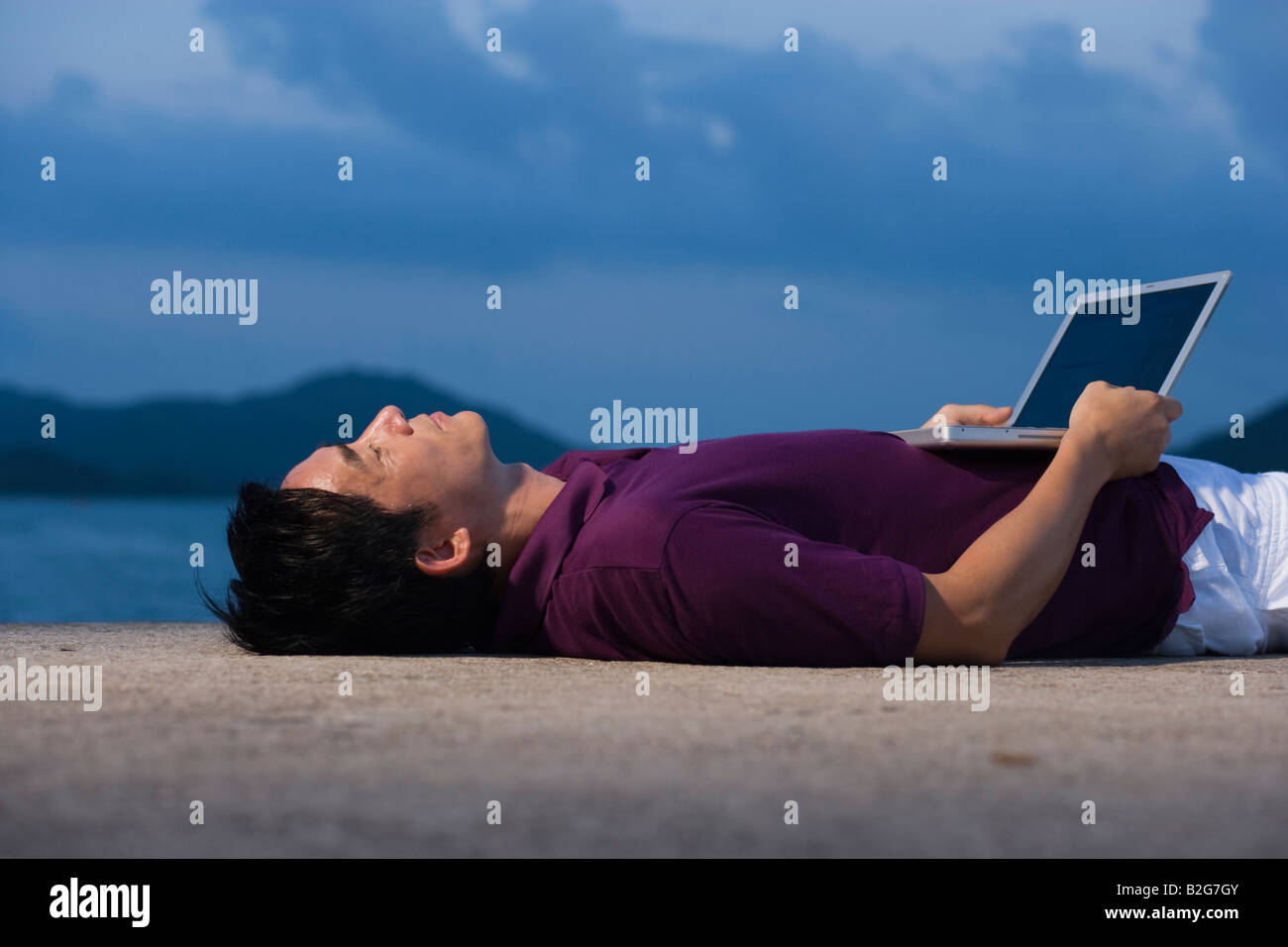 Side profile of mid adult man lying on the beach with a laptop Stock ...
