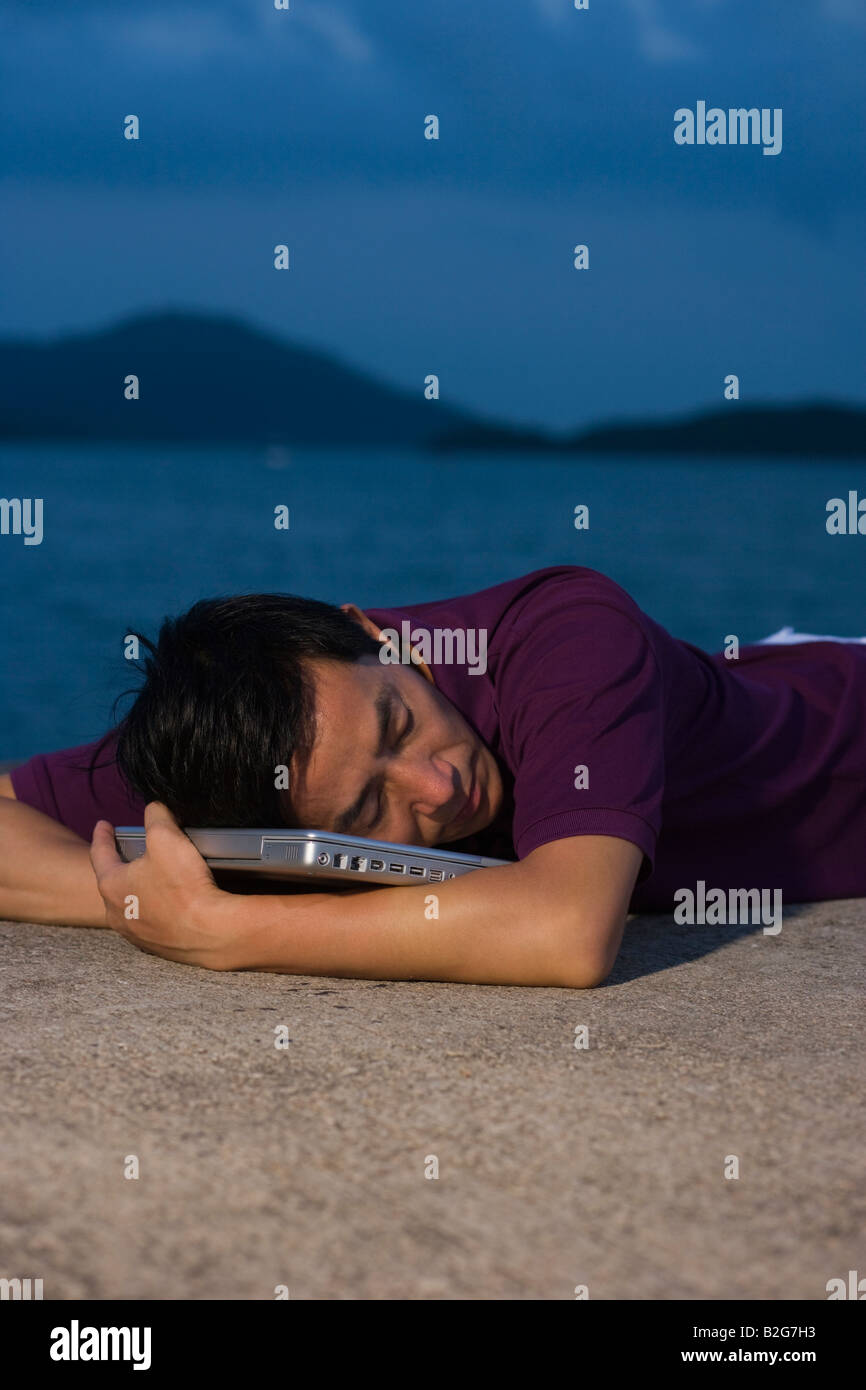 Side profile of mid adult man lying on the beach with a laptop Stock ...