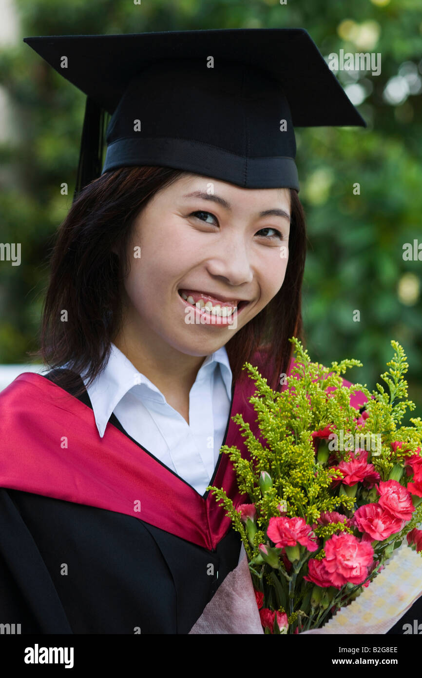 Portrait of a mid adult female graduate holding a bouquet of flowers