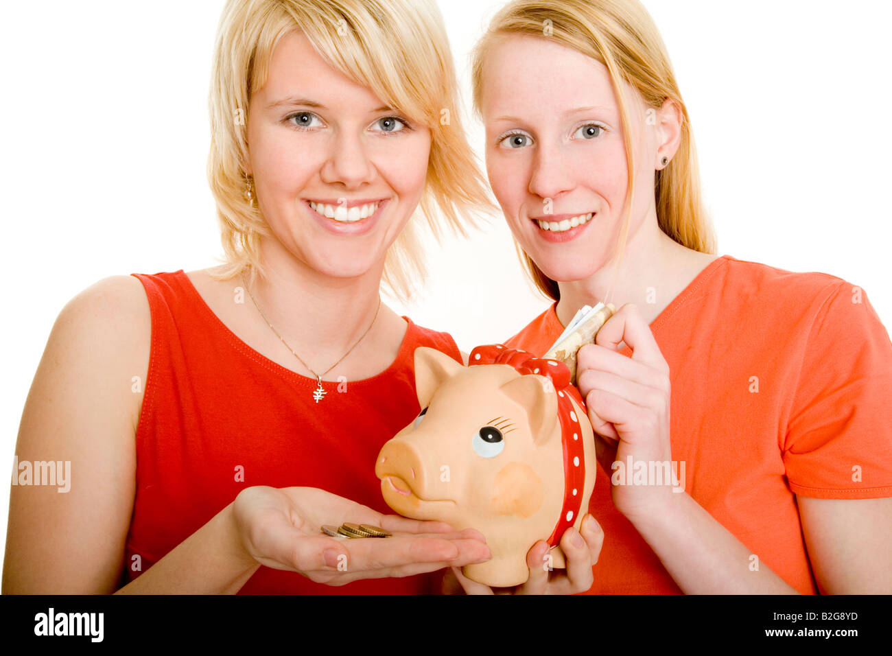 pair couple women young piggy bankZwei blonde Mädchen stecken Geldscheine und Münzen in ihr Sparschwein Models v l n r Lisa Marq Stock Photo