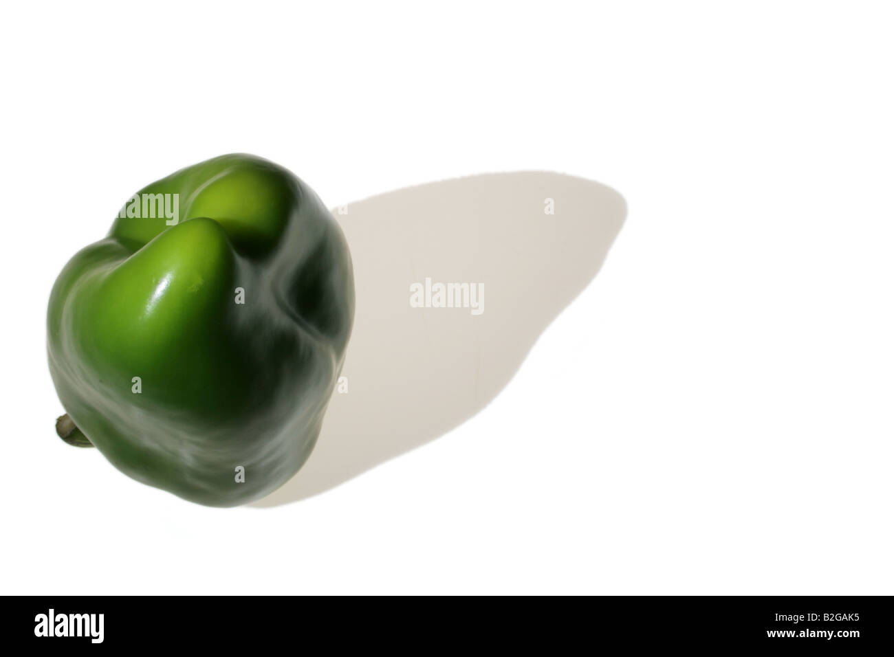 Green pepper on white background, ambiguously shaped, casting a shadow Stock Photo