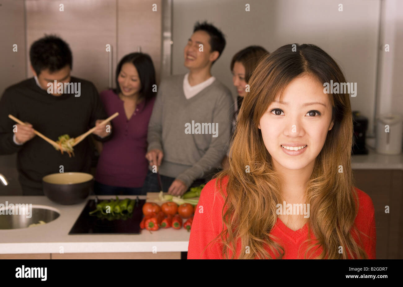 Portrait of a young woman with friends working in a kitchen Stock Photo