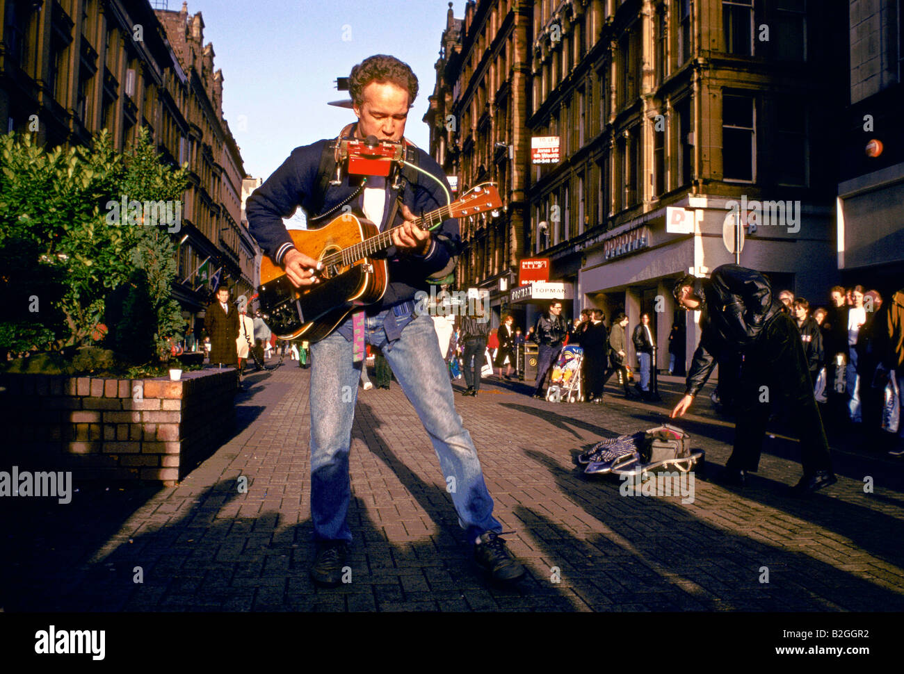 busker playing guitar and harmonica Stock Photo