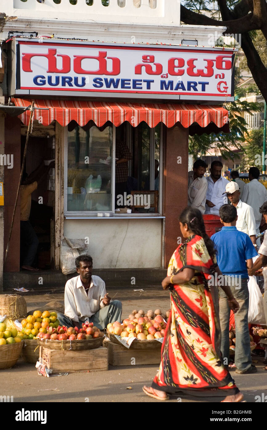 A man sells fruit on the pavement in front of the Guru Sweet Mart in Mysore.  The sweetshop is renowned for its Mysore Pak Stock Photo - Alamy