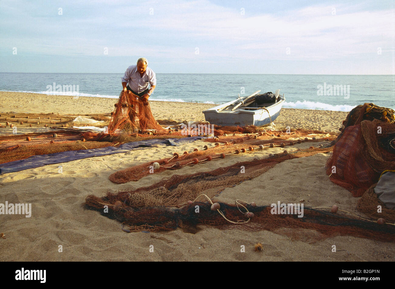 Old fisherman spreading his nets out on the sand. Bolnuevo beach. Murcia province. Spain. Stock Photo