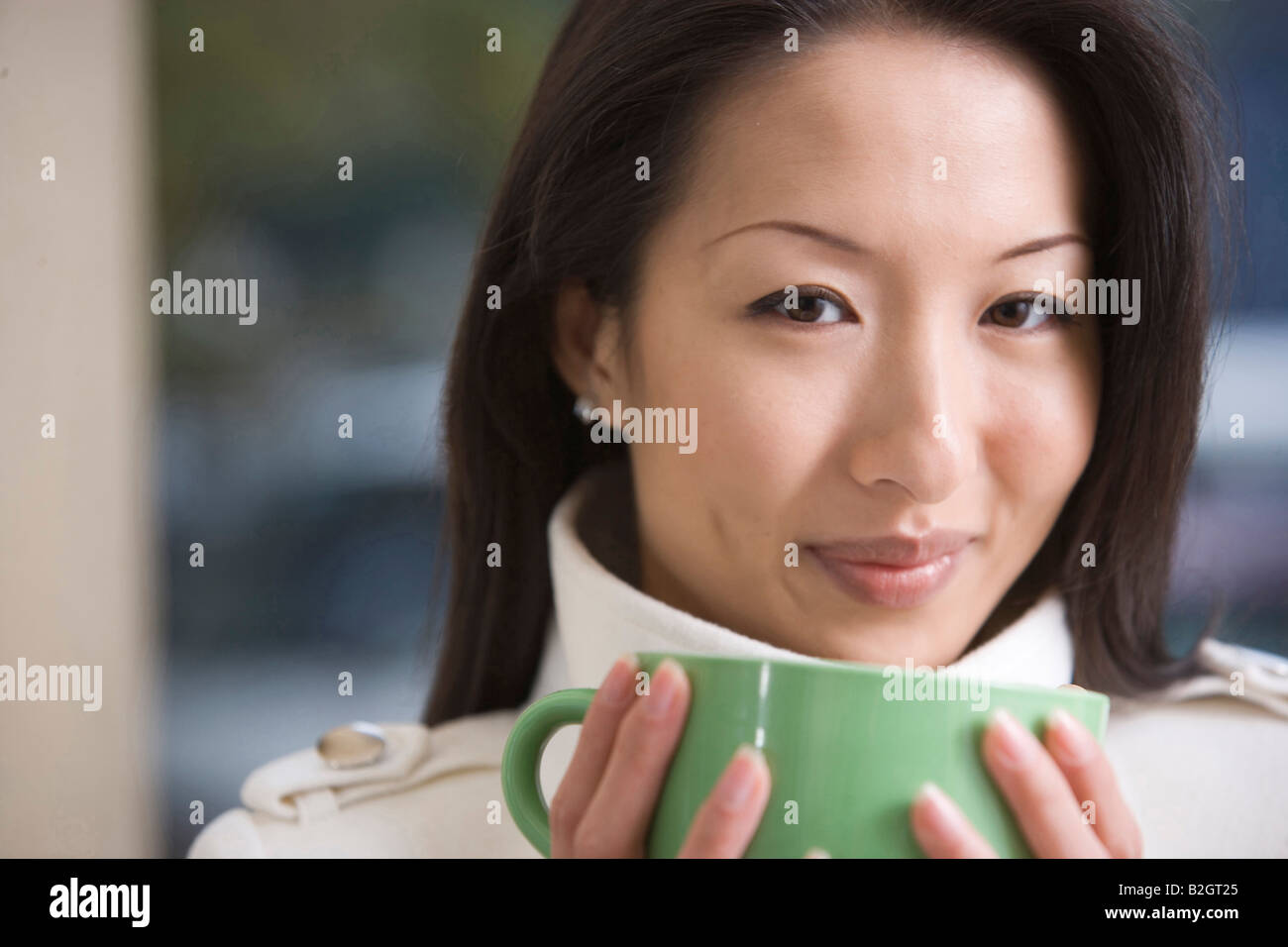 Portrait of a young woman holding a coffee cup and smiling Stock Photo ...