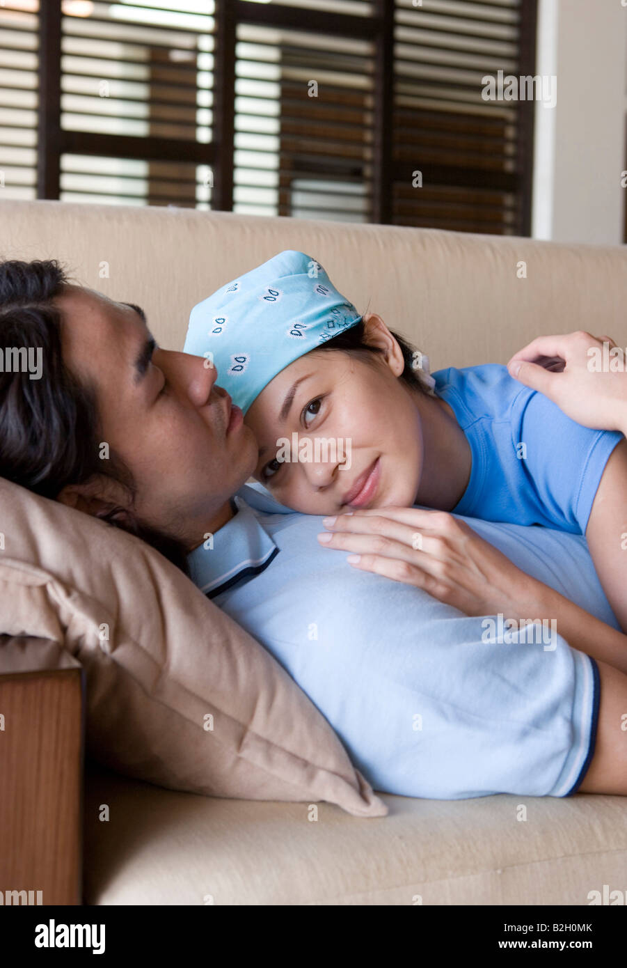 Side profile of a young man lying on a couch with a young woman Stock ...