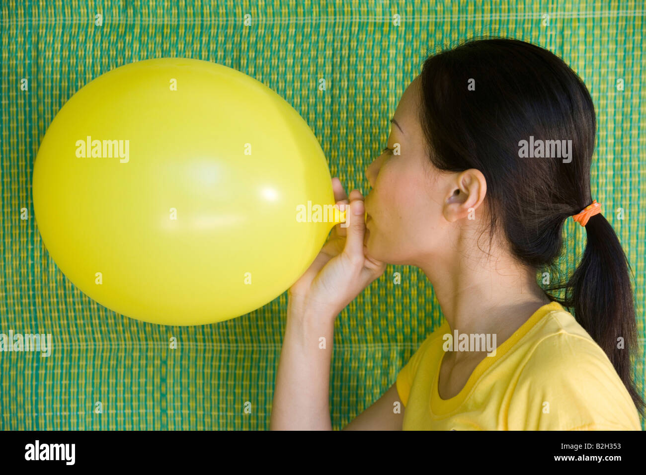Close-up of a young woman blowing a balloon Stock Photo