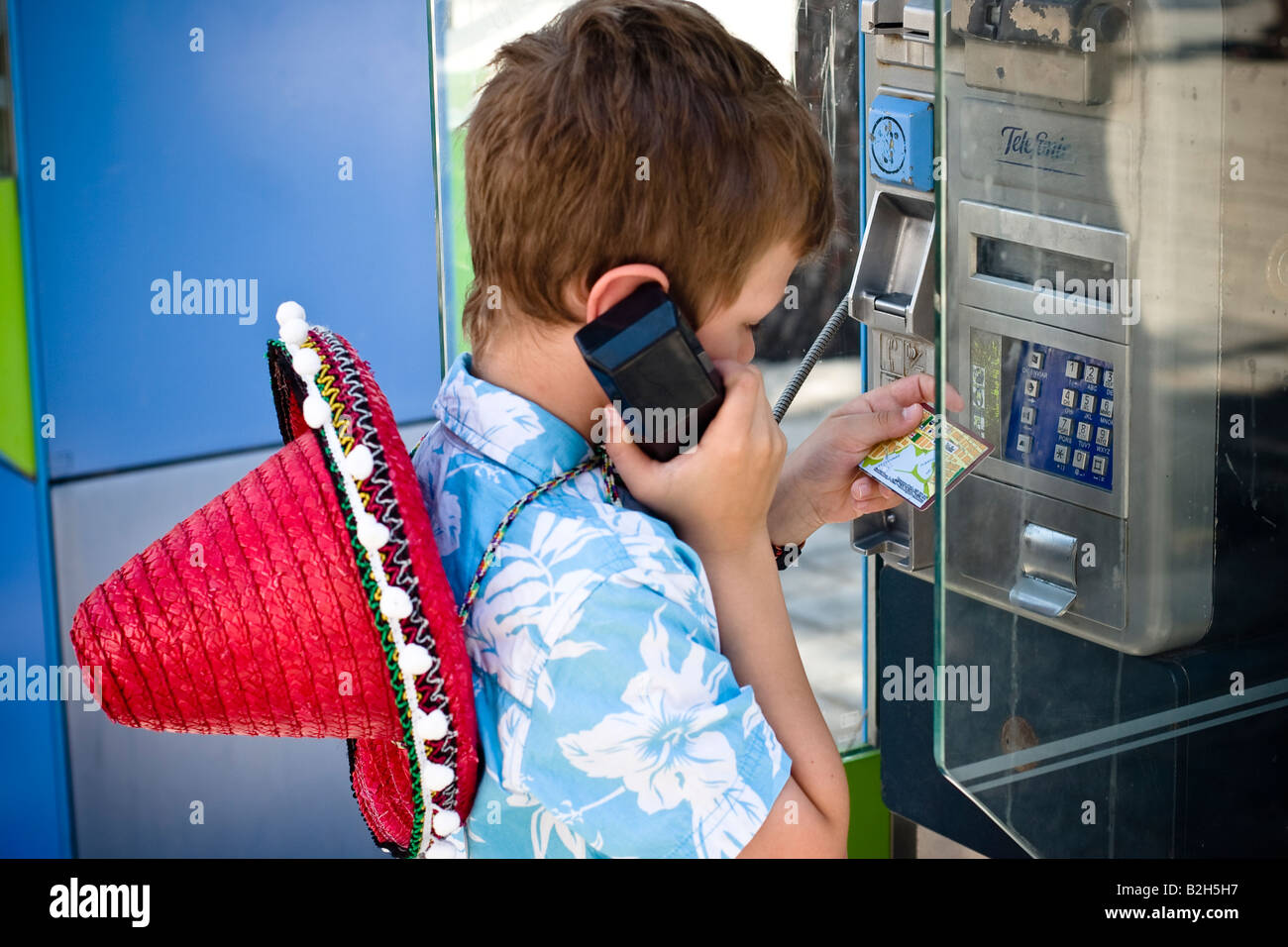 Young boy aged 7-8 makes phone call in public telephone box of the spanish telecom provider Telefonica in Cala Ratjada, Majorca Stock Photo