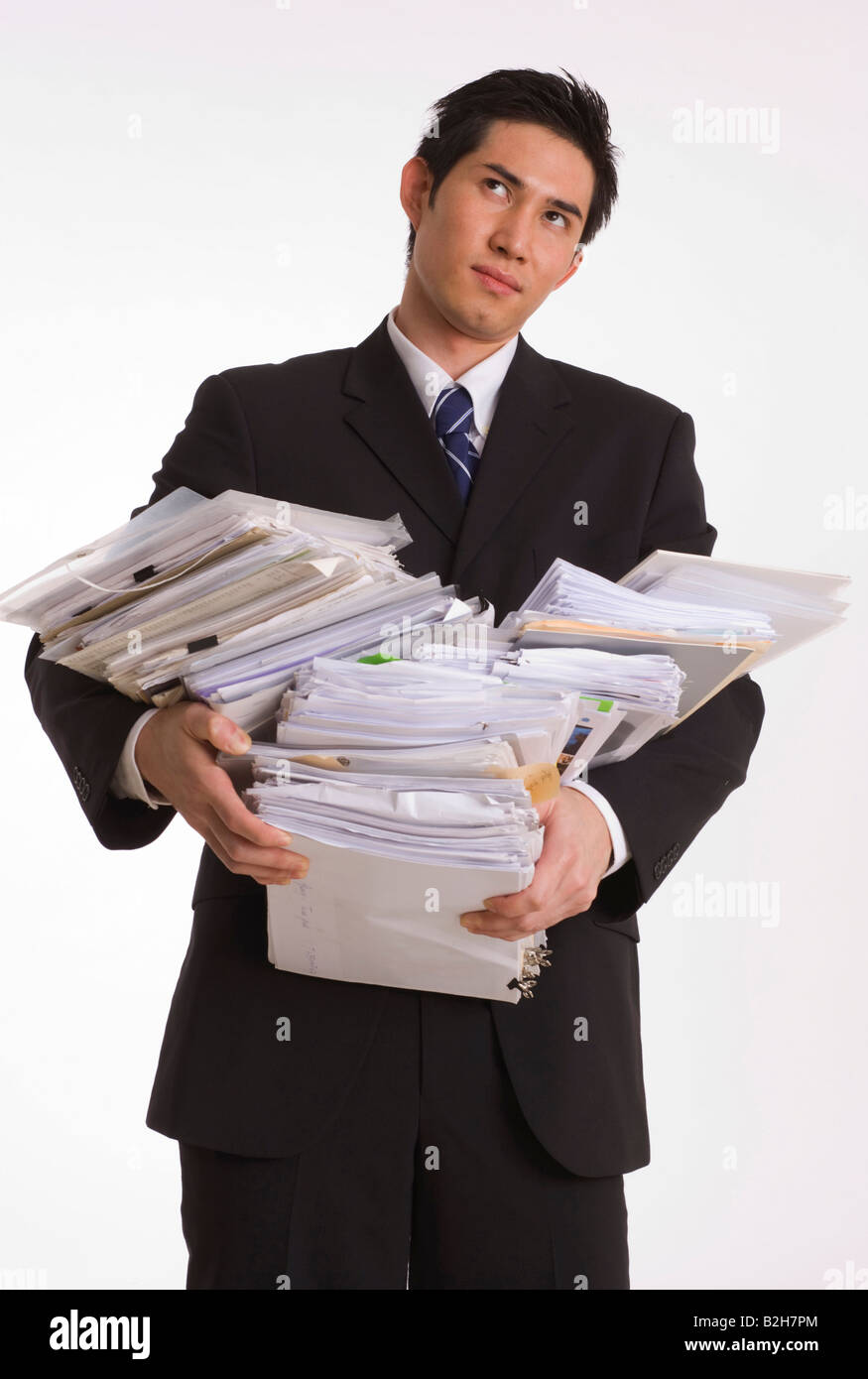 Businessman struggling to carry a stack of files Stock Photo Alamy