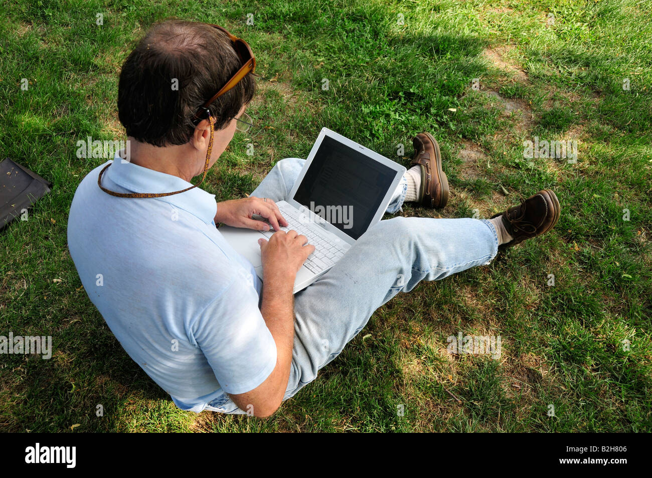 Adult male works on a laptop computer outside Stock Photo
