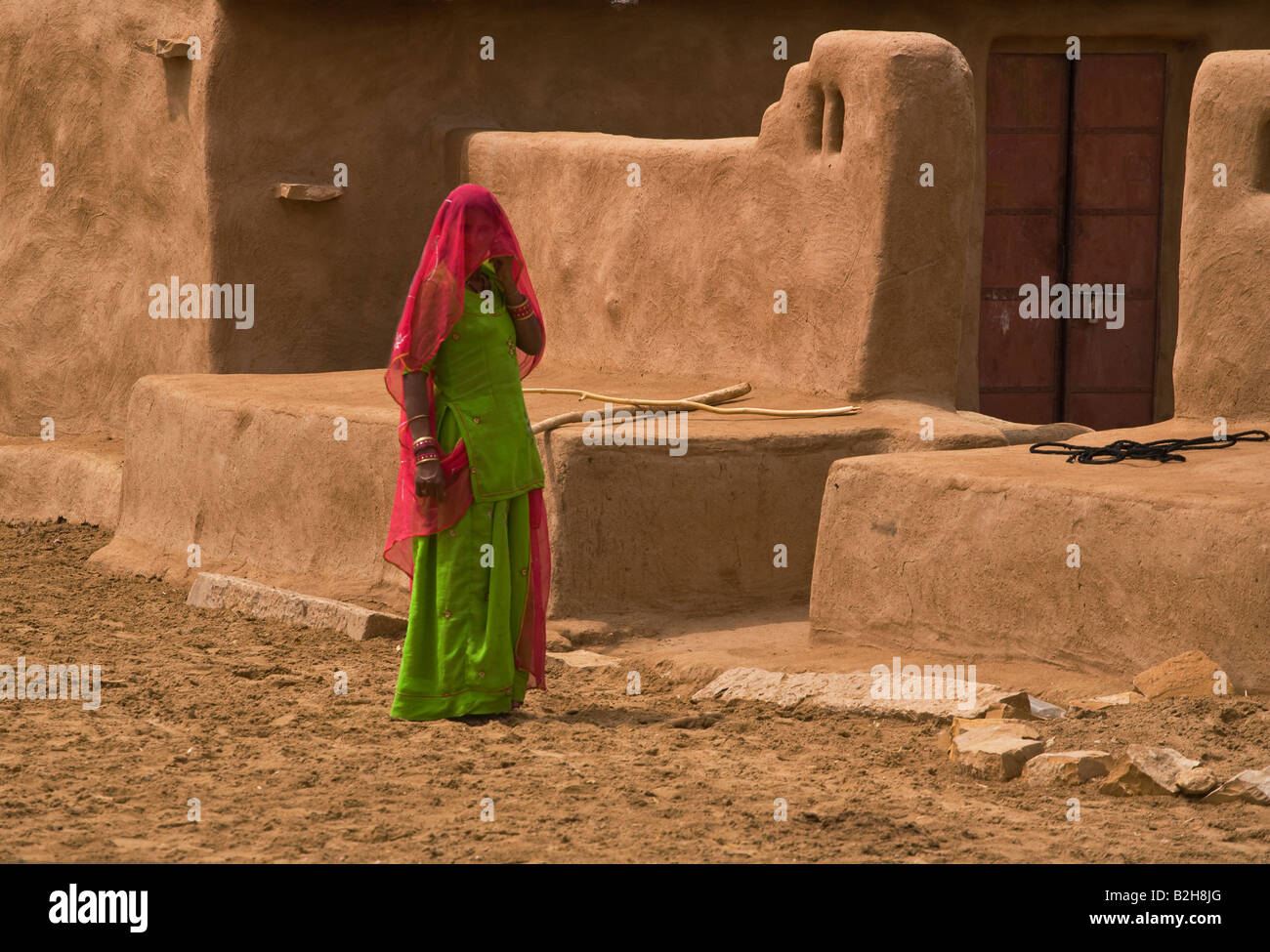 A BANJARI TRIBAL WOMAN and her classic MUD HOUSE in a village in the THAR DESERT near JAISALMER RAJASTHAN INDIA Stock Photo