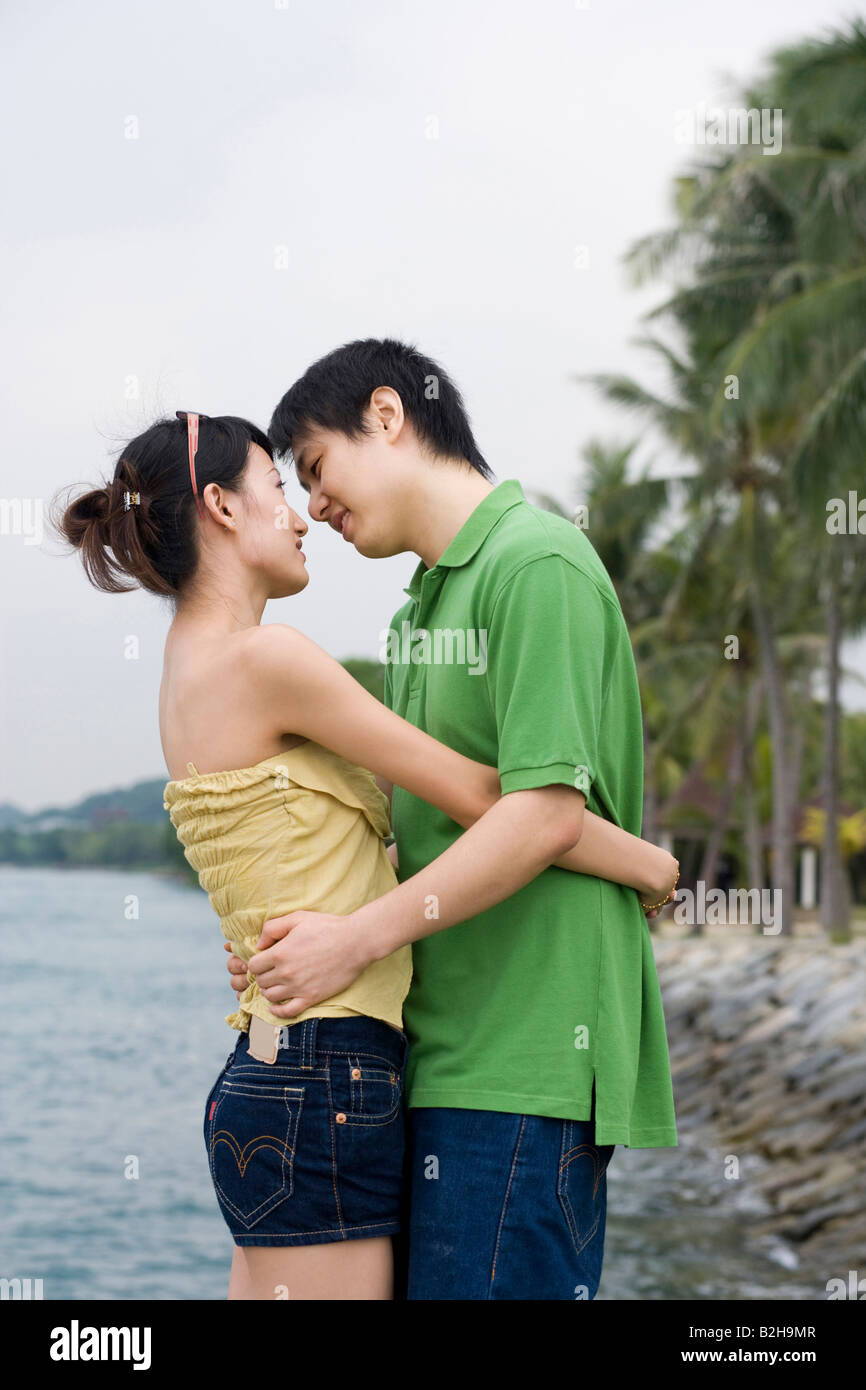 Side profile of a mid adult couple embracing each other on the beach ...