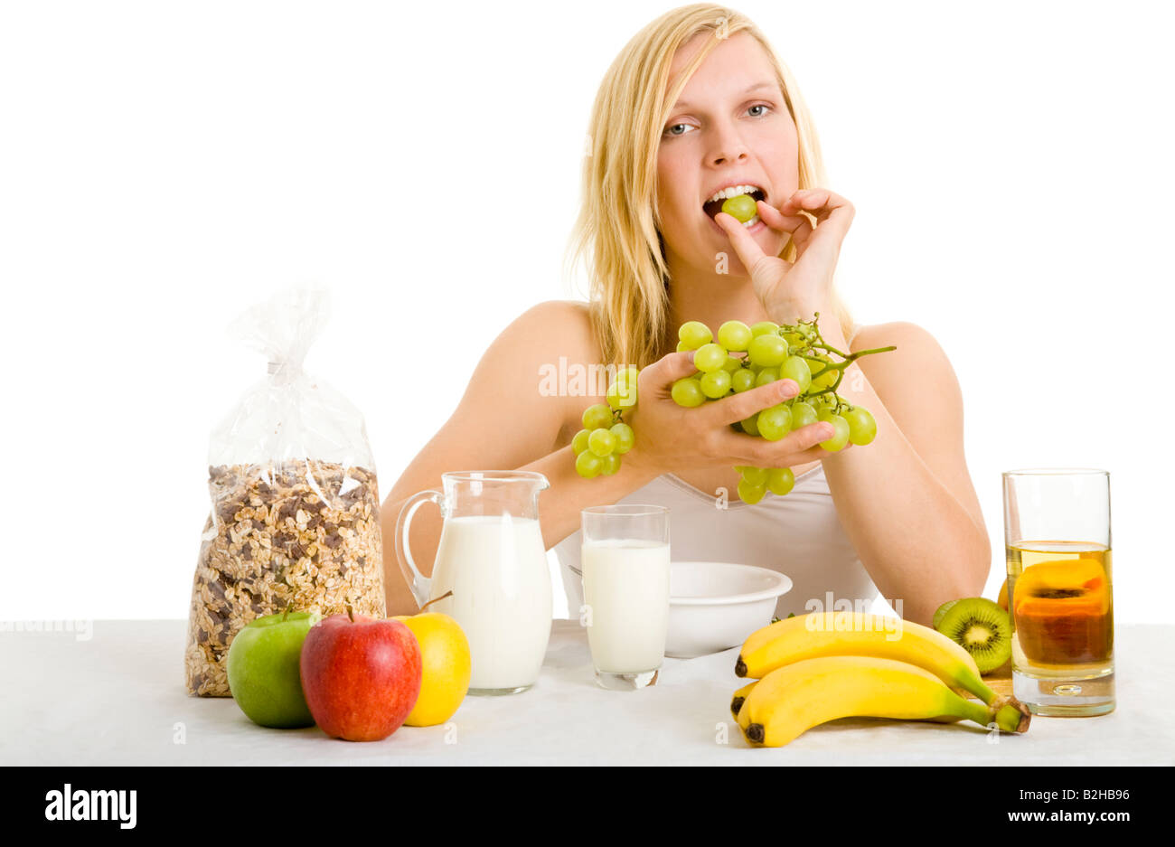 young blond woman breakfast fruits sound food morning bananas apples grapes body care wellness healthful eating Stock Photo