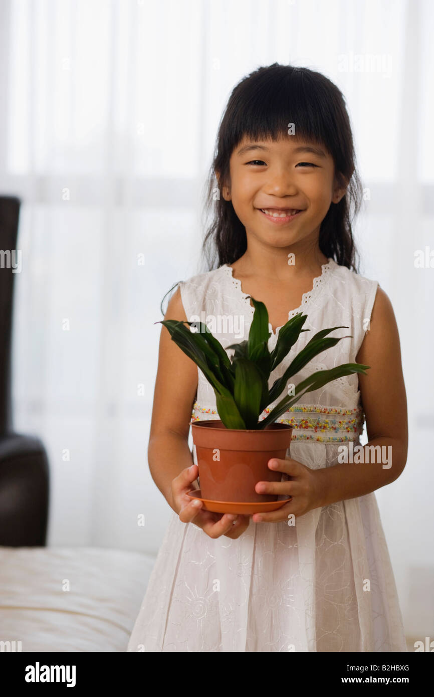 Portrait of a girl holding a potted plant and smiling, Singapore Stock ...