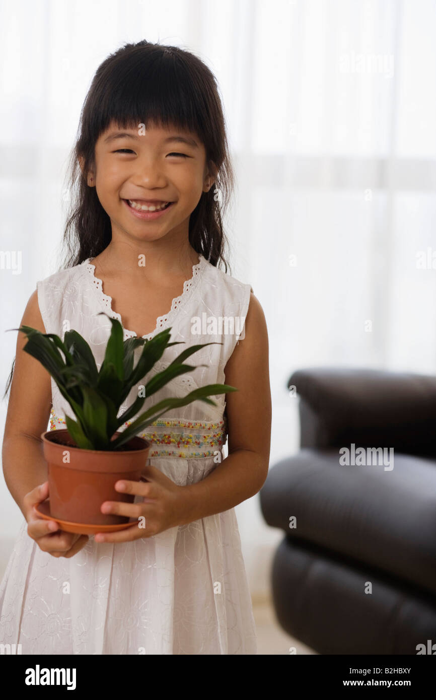 Portrait of a girl holding a potted plant and smiling, Singapore Stock ...