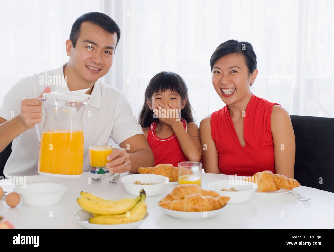 Portrait of a mid adult couple sitting at a breakfast table with their daughter Stock Photo