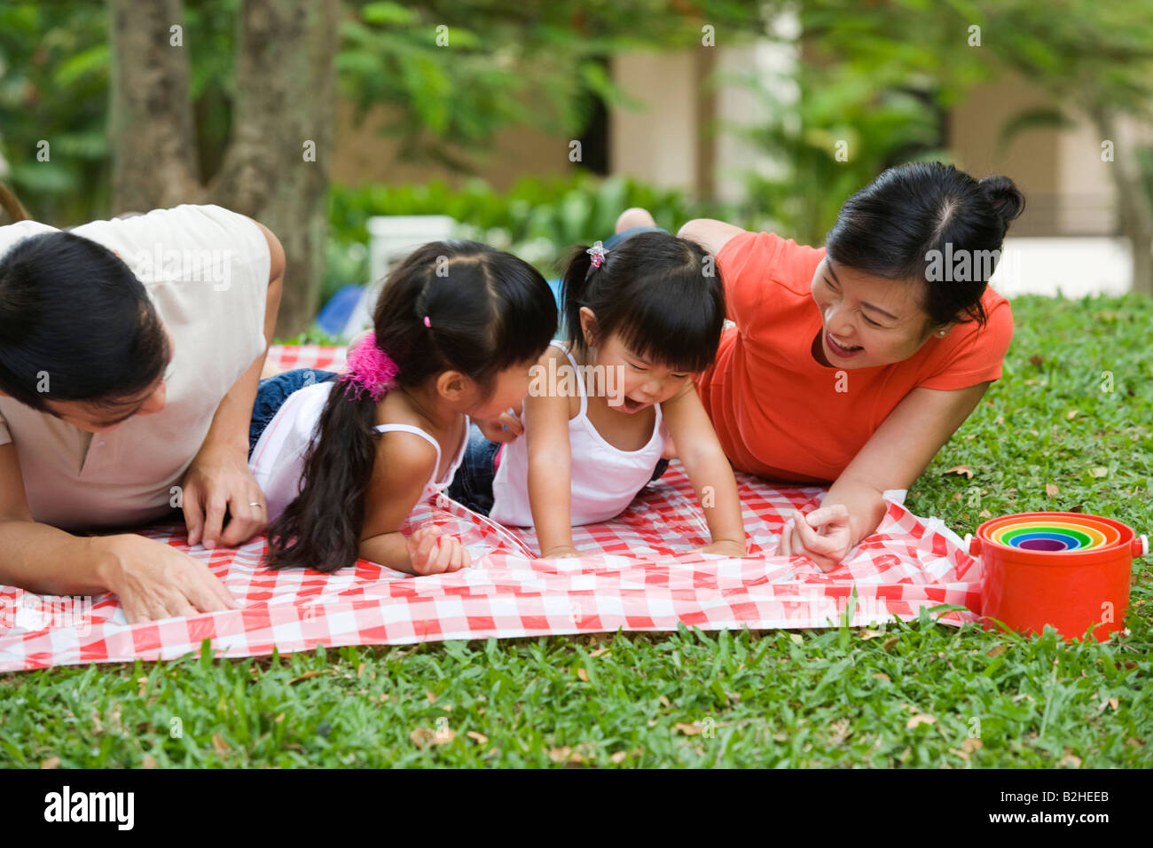 Mid adult couple lying on a picnic blanket with their two daughters and