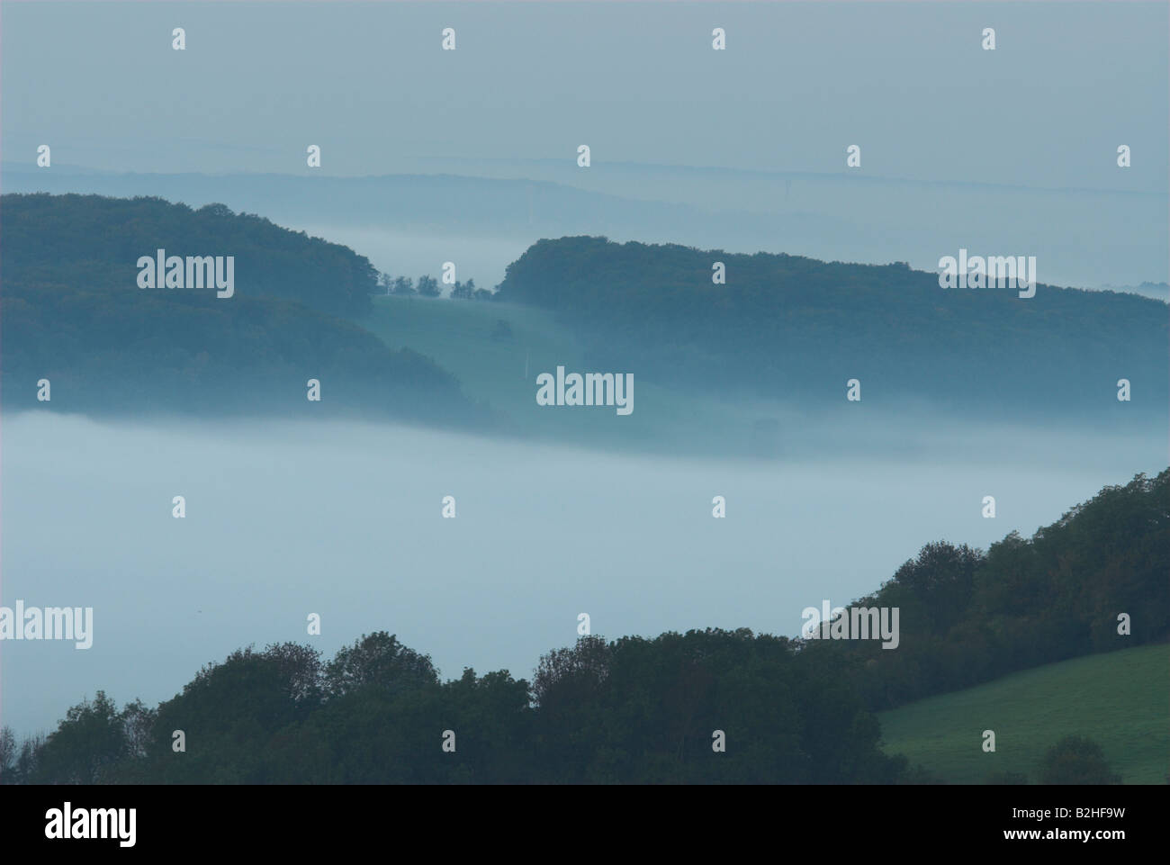 hills morning mist bliesgau germany landscape scenery morning moodHügel ragen aus dem Nebel im Bliesgau Stock Photo