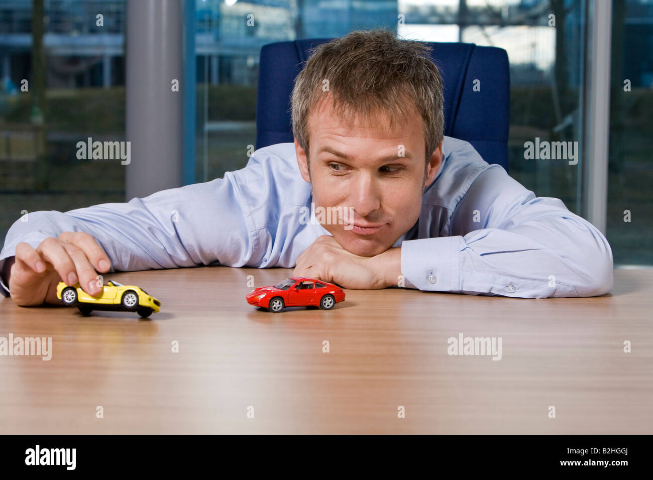 portrait of businessman playing with toy cars Stock Photo