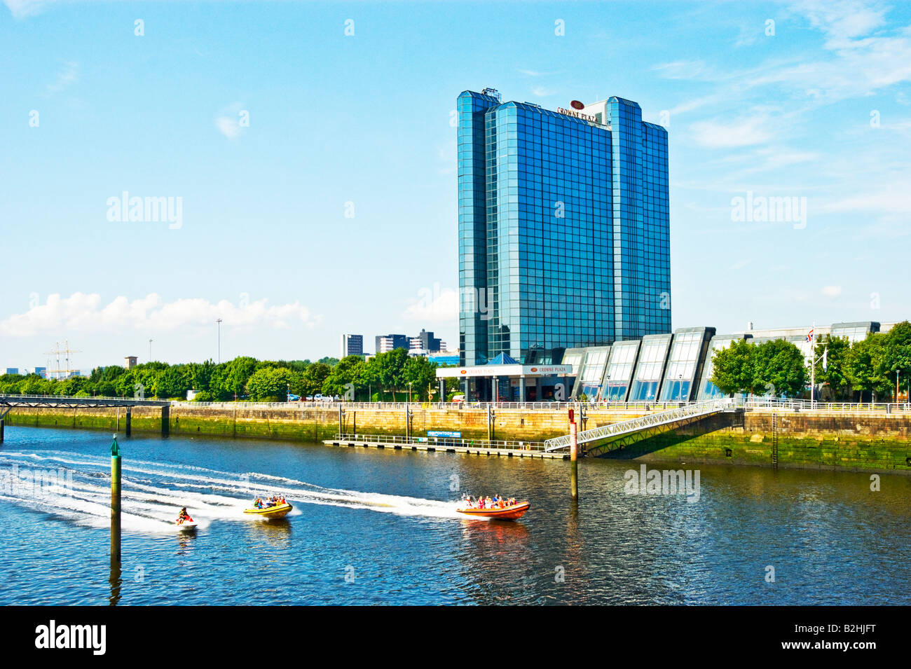 Speed boats pass by the Crowne Plaza Hotel on the River Clyde in Glasgow Scotland Stock Photo
