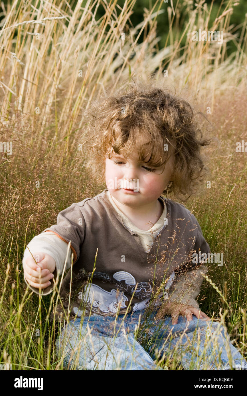 Young boy sitting in long grass Stock Photo