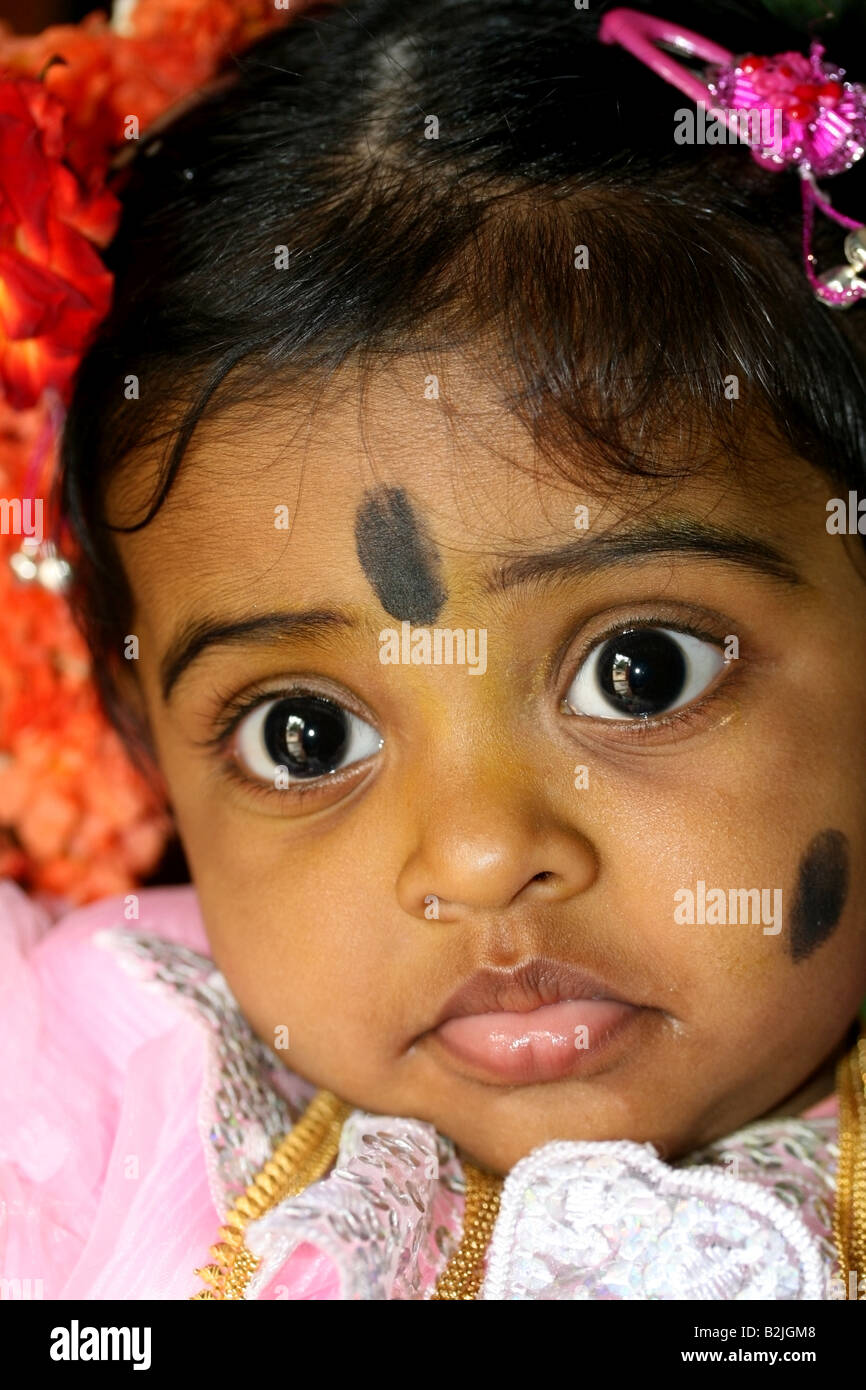 Portrait of a young Hindu girl with black spot make-up against the evil eye during her Namakaran naming ceremony , India Stock Photo