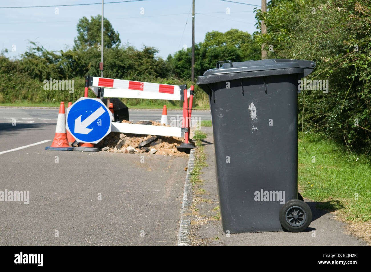 domestic refuse wheelie bin on the pavement awaiting collection with road works in the background Stock Photo