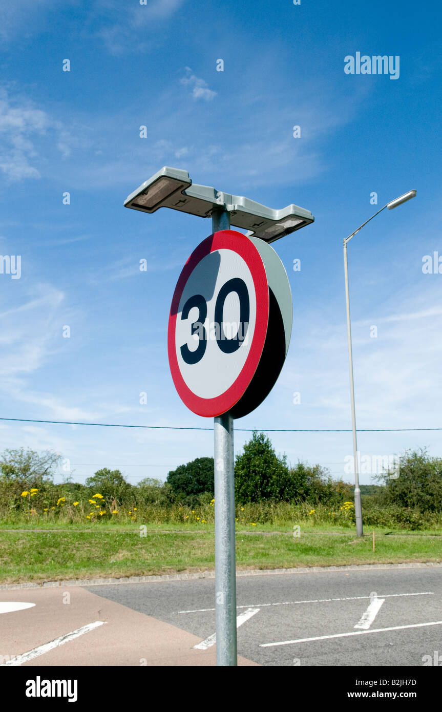 30 30mph miles per hour road sign with lights at the side of the road on a sunny day wide angle Stock Photo