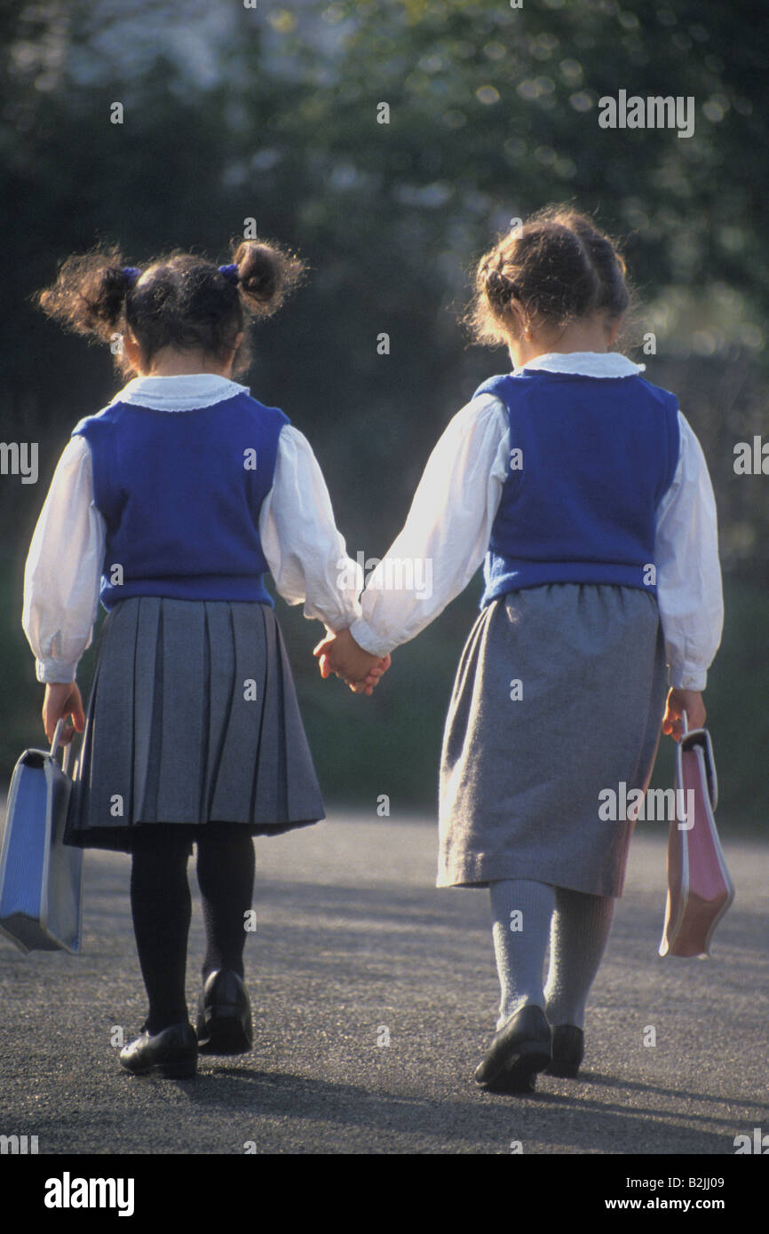 two little girls in school uniform walking to school Stock Photo - Alamy