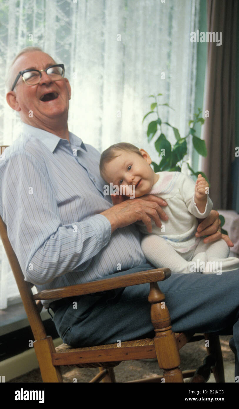 laughing grandpa holding baby in rocking chair Stock Photo