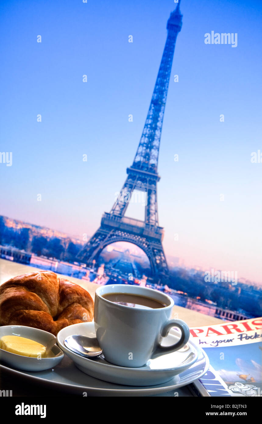 Parisian continental breakfast of coffee, croissant and butter on restaurant cafe bar table with Eiffel Tower in background Stock Photo