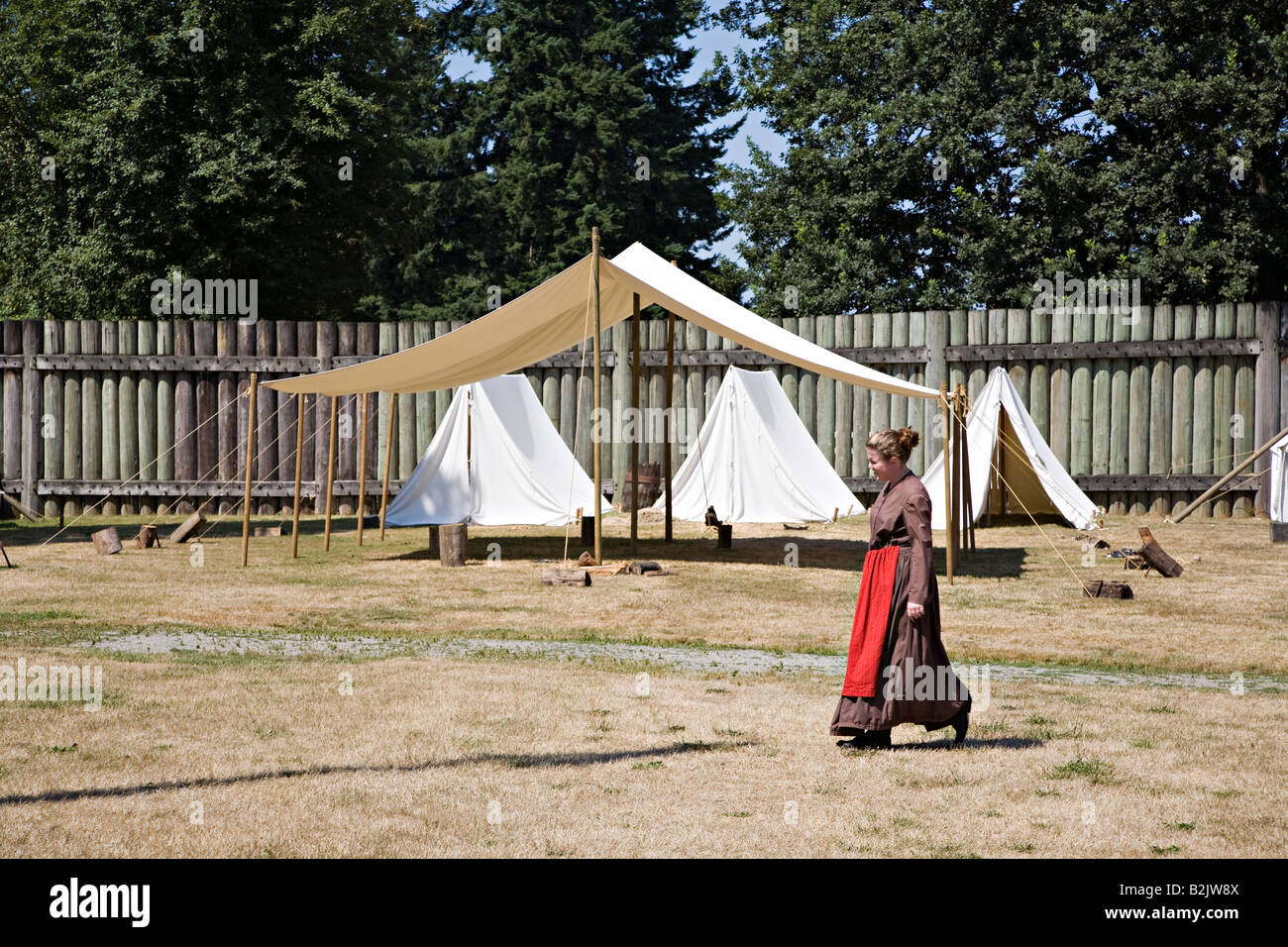 Woman in settler period costume walking past tents pitched at Fort Langley National Historic Site British Columbia Canada Stock Photo