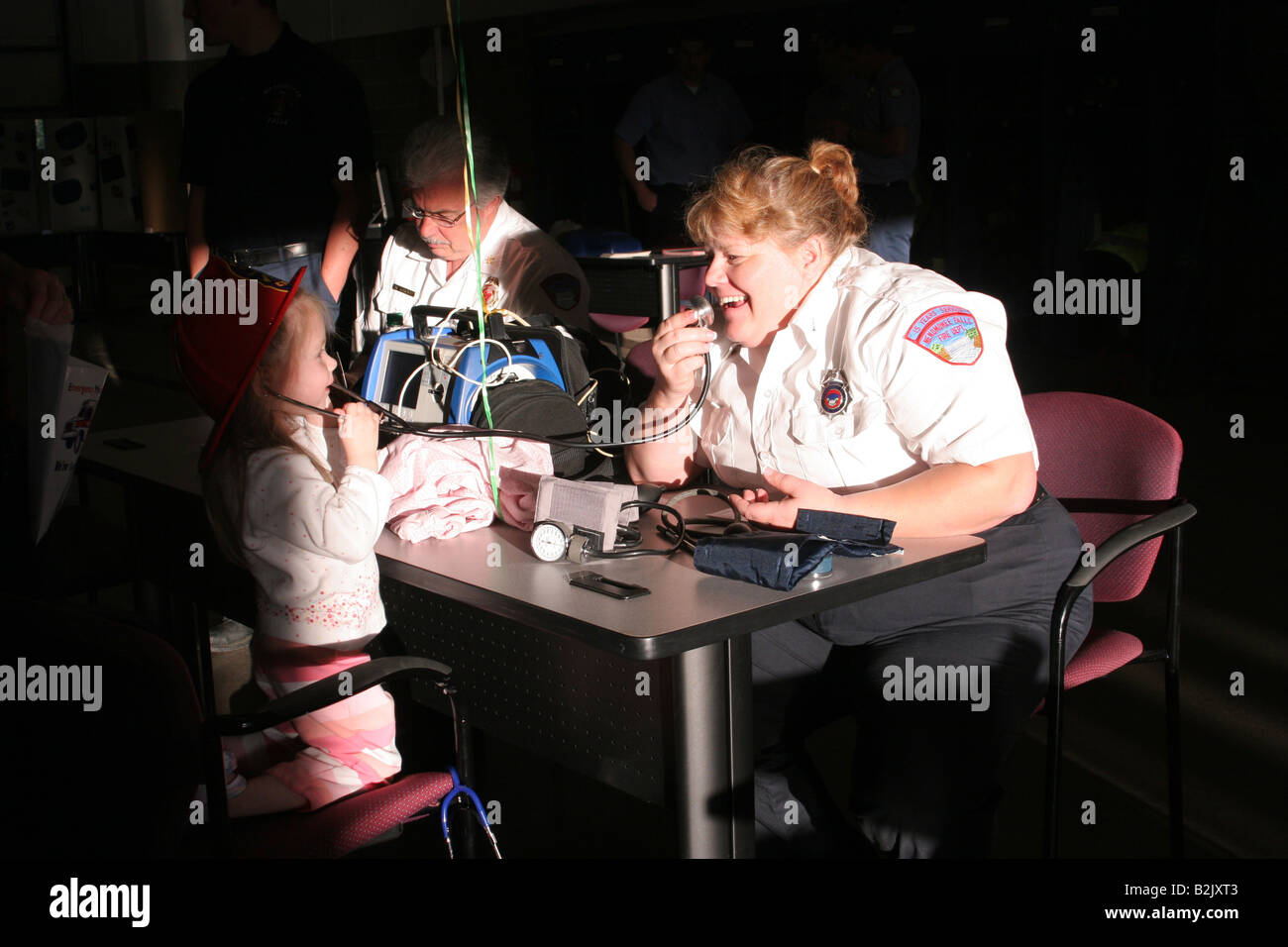 An EMT playing with a young girl while she is listening to the stethoscope Stock Photo