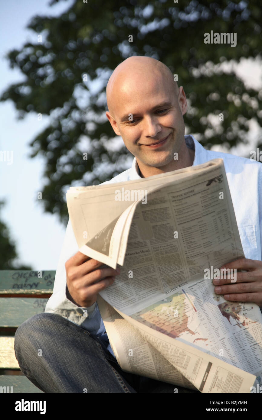 man on park bench reading newspaper Stock Photo - Alamy