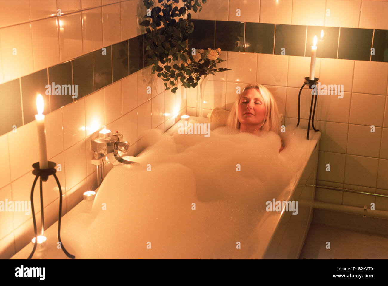 Relaxed blond woman in candle lit bubble bath Stock Photo - Alamy