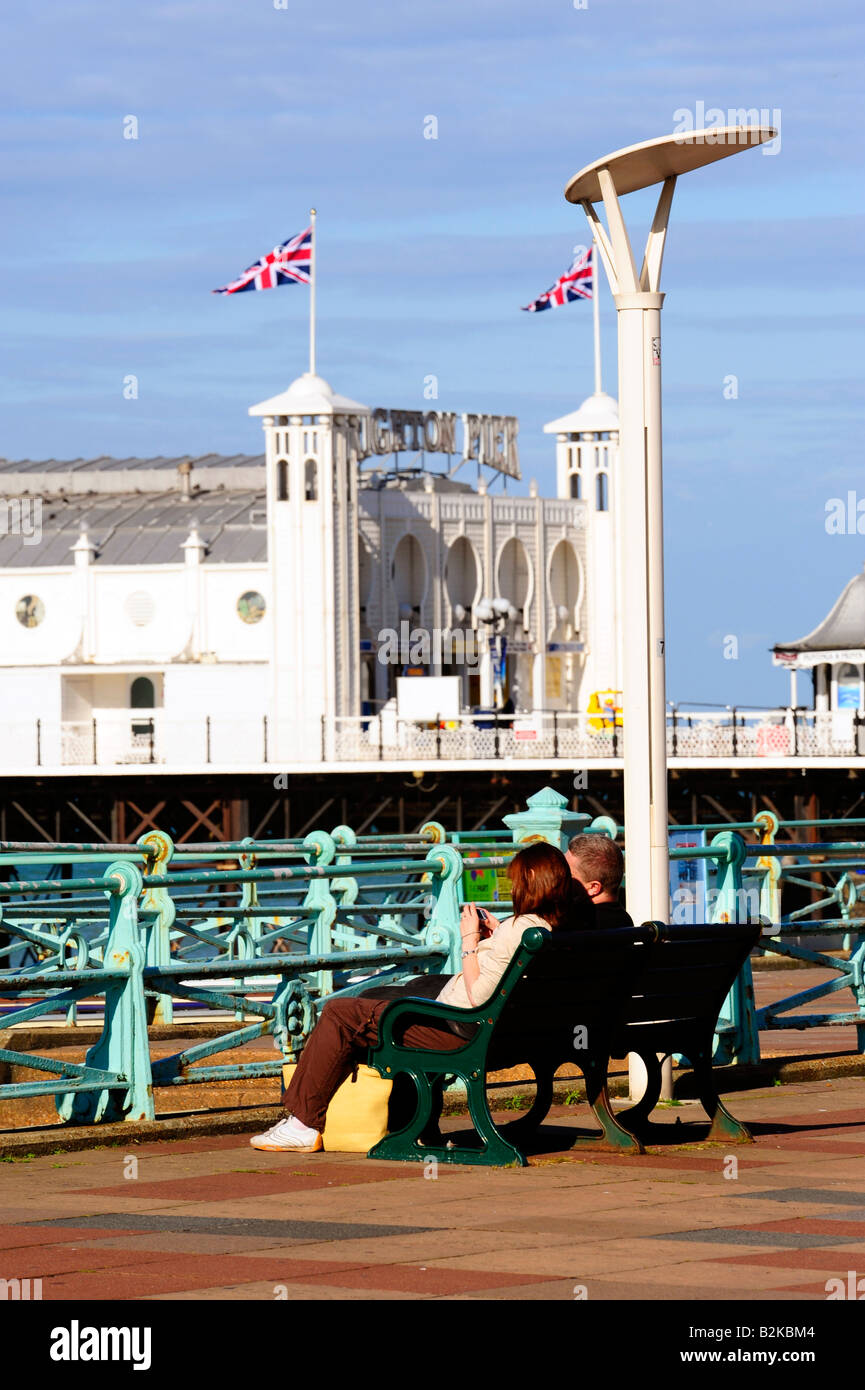 Couple on seafront looking at Brighton Pier and beach, sea Stock Photo
