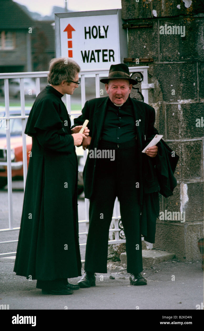 TWO PRIESTS BY HOLY WATER SIGN IN KNOCK CO CLARE Stock Photo