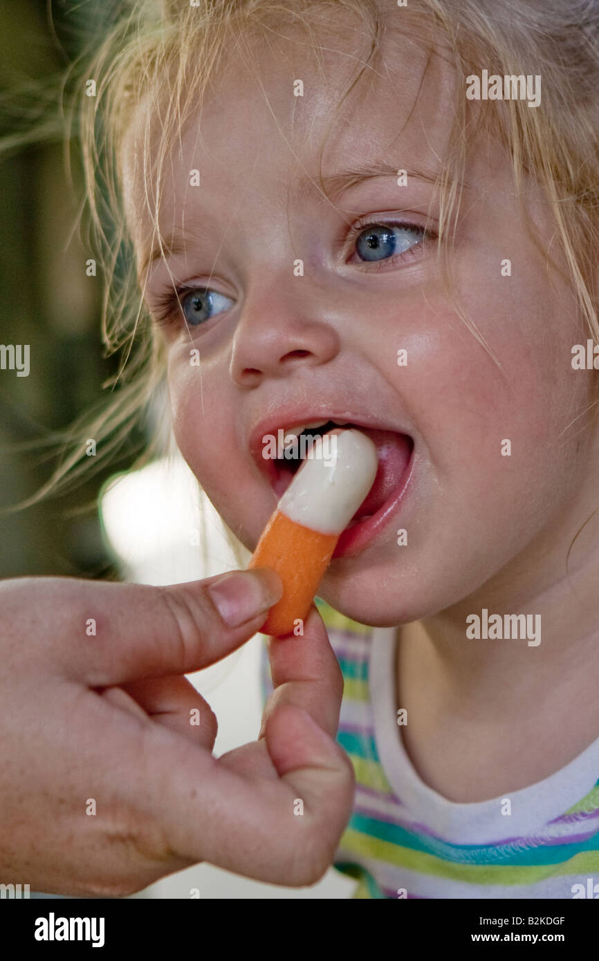 Female Toddler Eating a Carrot with Blue Cheese Dip Stock Photo