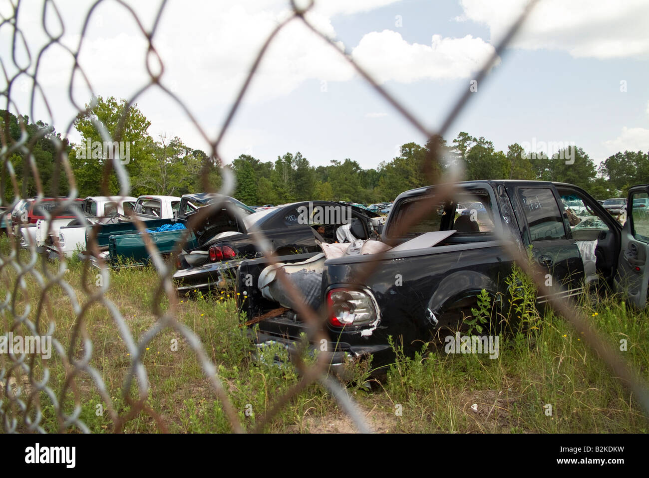 A row of wrecked or scrapped vehicles taken from behind a fence Stock Photo