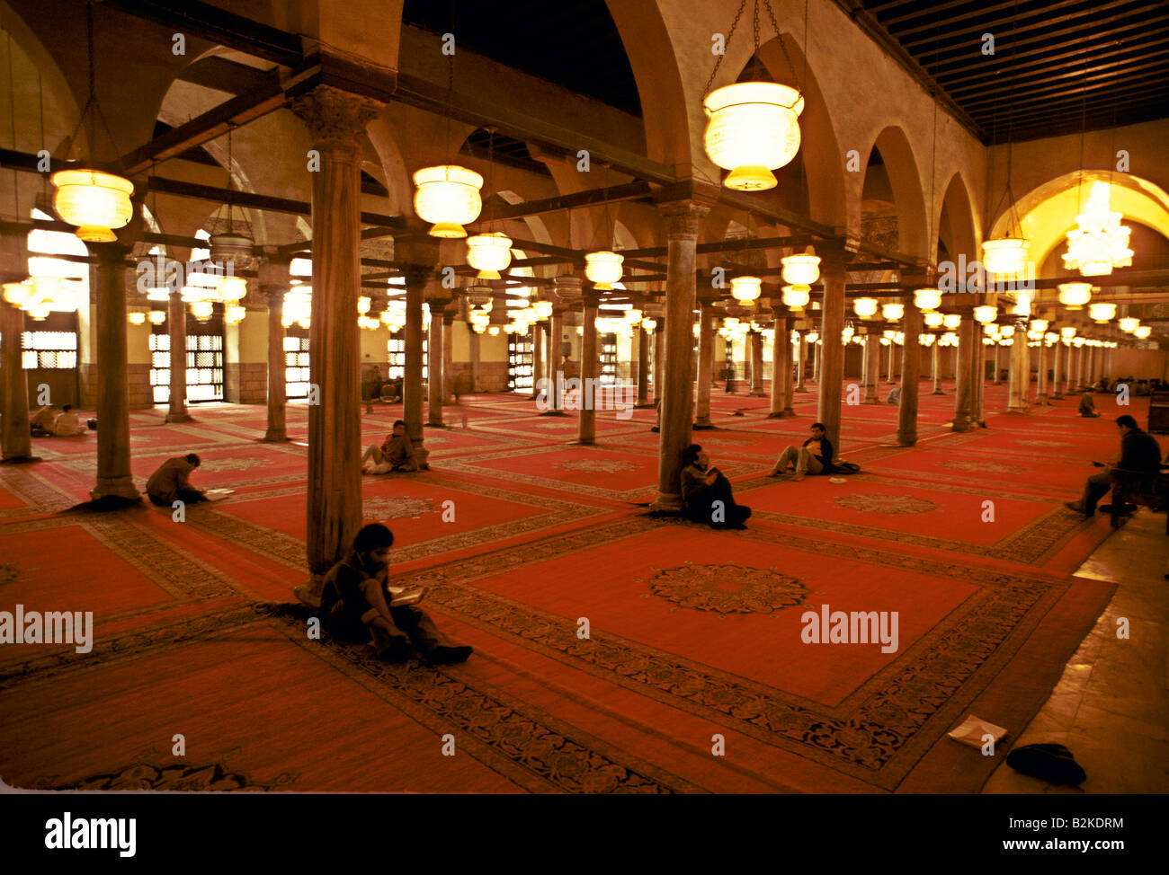 people leaning against pillars reading scripts sitting on carpets inside mosque cairo egypt Stock Photo