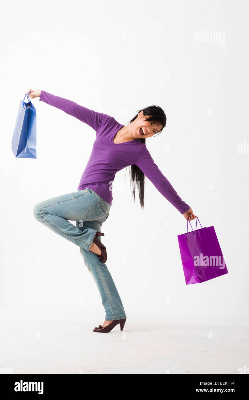 Side profile of a young woman carrying shopping bags and laughing Stock ...